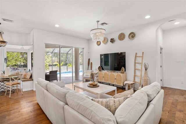 living area with arched walkways, wood-type flooring, recessed lighting, and baseboards