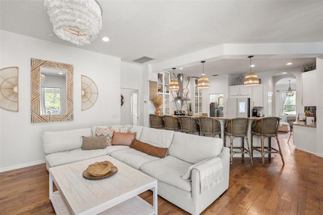 living area with a chandelier, hardwood / wood-style flooring, baseboards, recessed lighting, and arched walkways