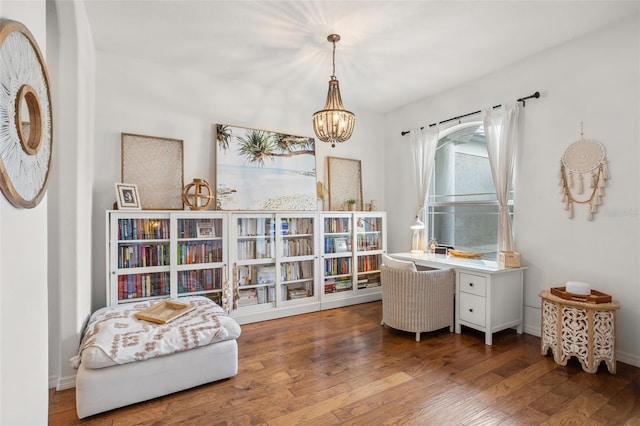 living area featuring wood finished floors, a chandelier, and baseboards