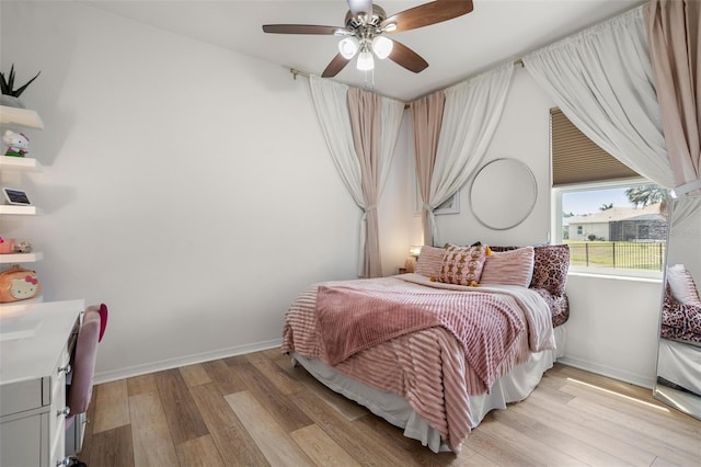 bedroom featuring light wood-style flooring, a ceiling fan, and baseboards