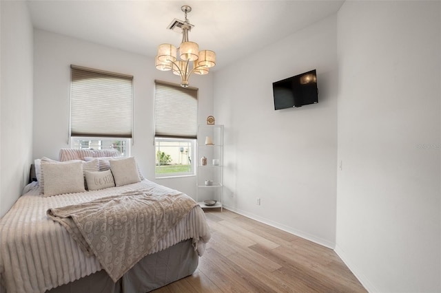 bedroom featuring a chandelier, wood finished floors, and baseboards