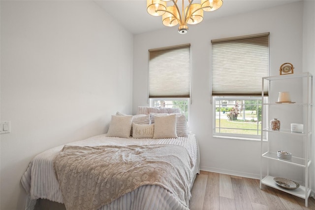 bedroom with a chandelier, wood finished floors, and baseboards