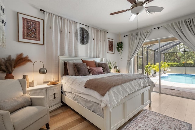 bedroom featuring access to exterior, a sunroom, light wood-type flooring, and a ceiling fan
