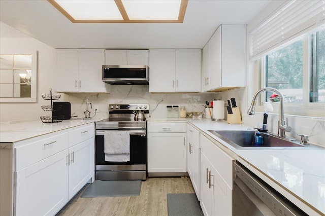 1010 Oakhill St, Seffner, FL 33584 - kitchen with stainless steel appliances, a sink, white cabinets, light wood-type flooring, and decorative backsplash