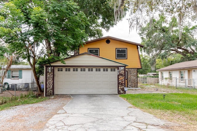1010 Oakhill St, Seffner, FL 33584 - view of front of house with asphalt driveway, stone siding, a garage, and fence