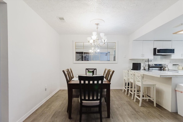 1010 Oakhill St, Seffner, FL 33584 - dining space featuring wood finished floors, a chandelier, a textured ceiling, and baseboards