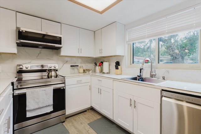 1010 Oakhill St, Seffner, FL 33584 - kitchen featuring appliances with stainless steel finishes, a sink, white cabinetry, light countertops, and backsplash