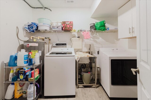 1010 Oakhill St, Seffner, FL 33584 - laundry area with independent washer and dryer, light wood-type flooring, and cabinet space