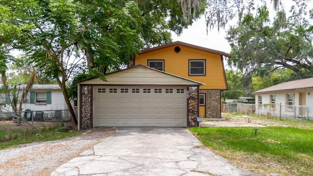 1010 Oakhill St, Seffner, FL 33584 - view of front of house featuring stone siding, driveway, fence, and a garage