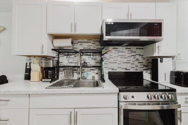 1010 Oakhill St, Seffner, FL 33584 - kitchen featuring stainless steel appliances, a sink, white cabinetry, and decorative backsplash