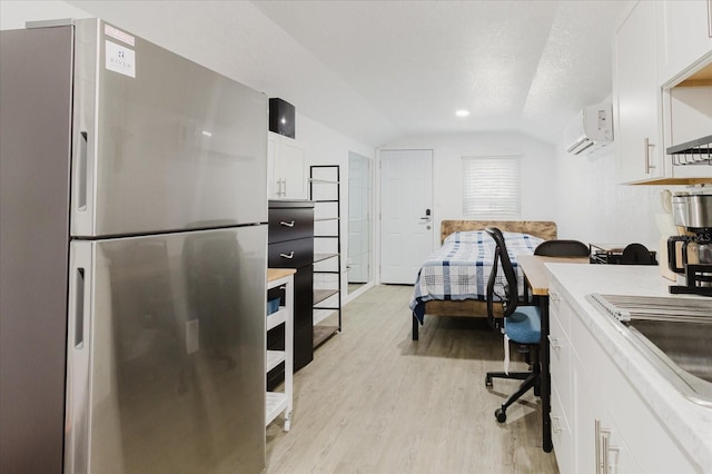 1010 Oakhill St, Seffner, FL 33584 - kitchen with freestanding refrigerator, lofted ceiling, light wood-type flooring, white cabinets, and light countertops