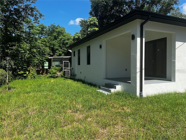 4241 E Palifox St, Tampa, FL 33610 - view of property exterior featuring stucco siding, a lawn, and a sunroom
