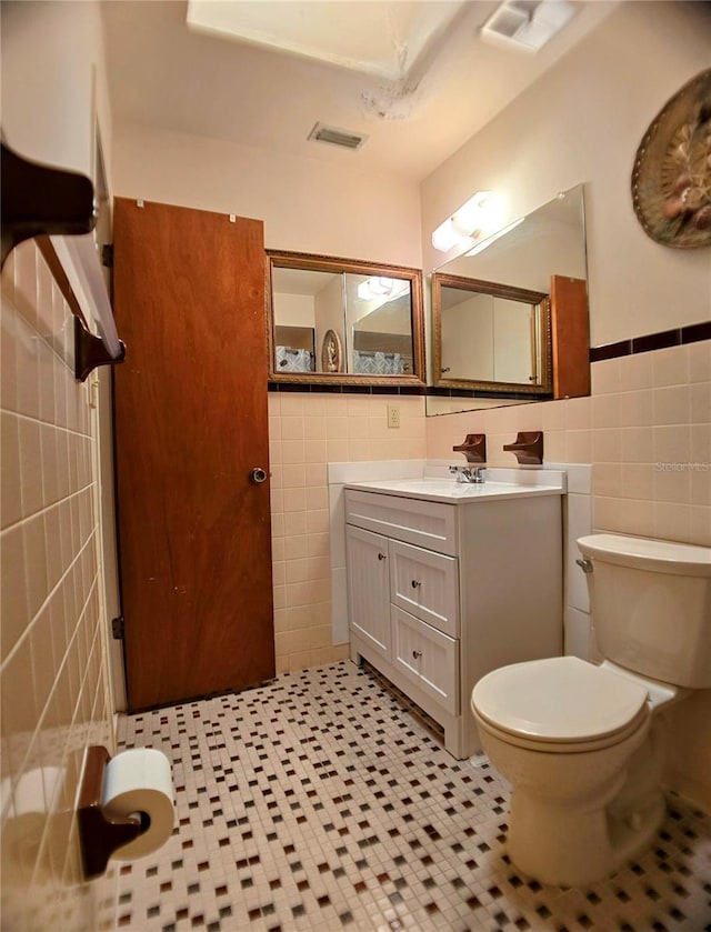 1262 Jeffords St, Clearwater, FL 33756 - bathroom with tile walls, toilet, vanity, a wainscoted wall, and tile patterned flooring