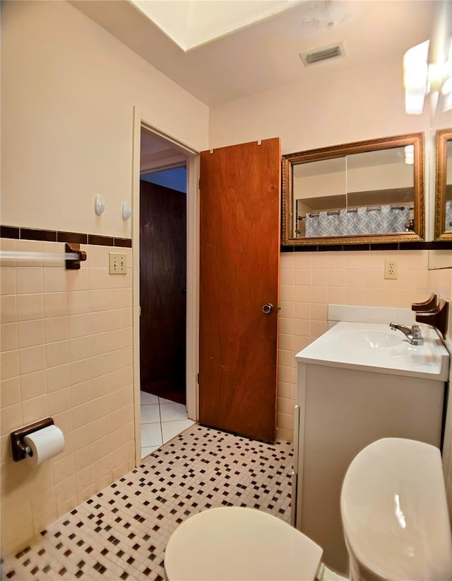 1262 Jeffords St, Clearwater, FL 33756 - bathroom with tile walls, toilet, a wainscoted wall, vanity, and tile patterned flooring