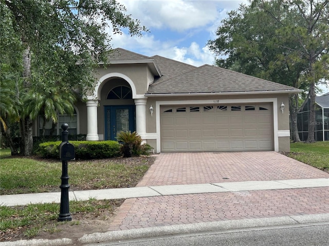 view of front facade featuring stucco siding, decorative driveway, a garage, and roof with shingles