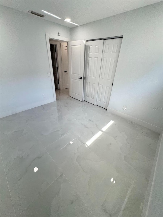 1778 New Hampshire Ave NE, Saint Petersburg, FL 33703 - unfurnished bedroom with light marble finish floors, baseboards, and a closet