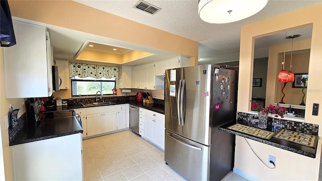 3907 Orchard Hill Cir, Palm Harbor, FL 34684 - kitchen featuring stainless steel appliances, a sink, a raised ceiling, dark countertops, and white cabinets