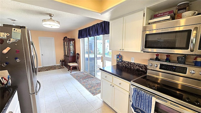 3907 Orchard Hill Cir, Palm Harbor, FL 34684 - kitchen with appliances with stainless steel finishes, light tile patterned floors, white cabinetry, dark countertops, and a textured ceiling