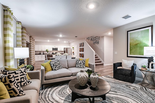 living area featuring stairs, baseboards, light wood-style flooring, and recessed lighting