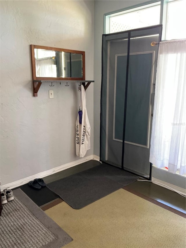 mudroom with baseboards, carpet floors, and a textured wall