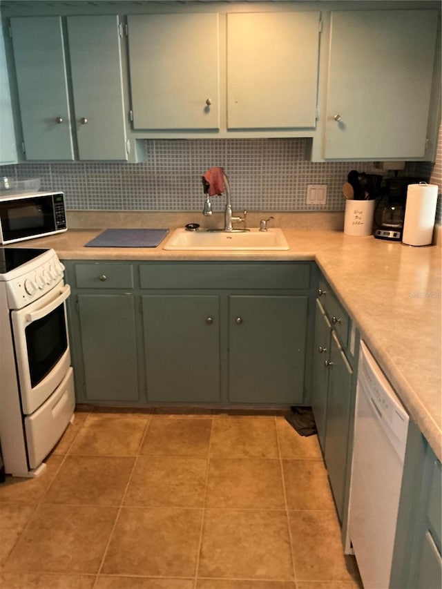 kitchen featuring white appliances, a sink, tasteful backsplash, and light countertops