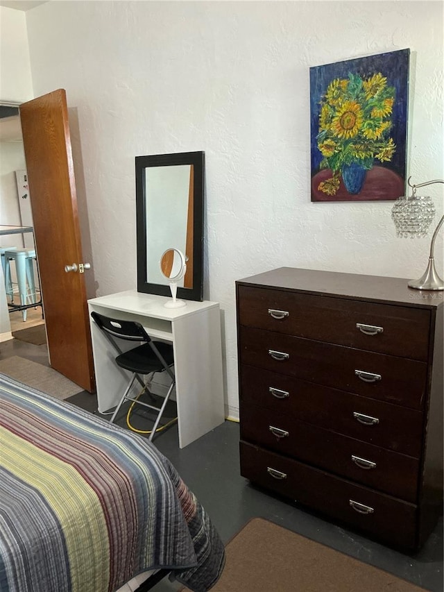 bedroom featuring concrete floors and a textured wall