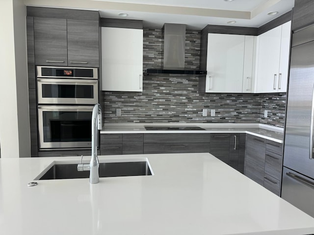 kitchen featuring wall chimney exhaust hood, a sink, modern cabinets, stainless steel appliances, and recessed lighting