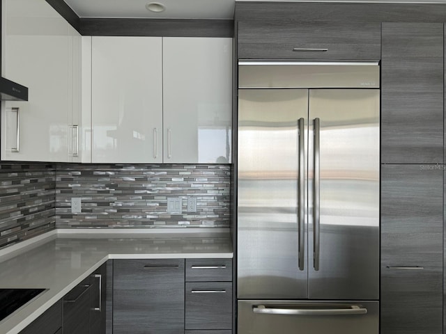 kitchen featuring stainless steel built in fridge, light countertops, decorative backsplash, and modern cabinets