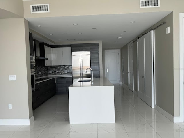 kitchen featuring stainless steel built in fridge, backsplash, baseboards, a sink, and modern cabinets