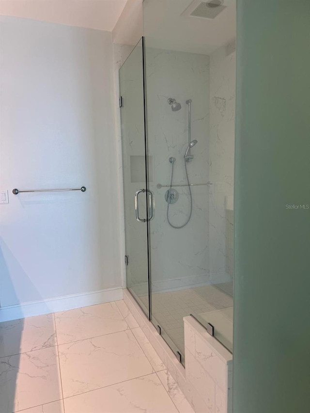 full bath featuring a marble finish shower, marble finish floors, and baseboards