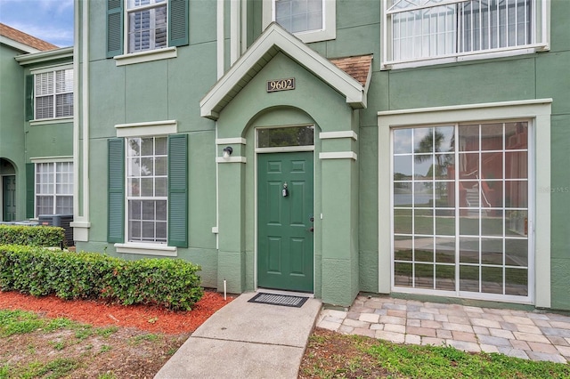 9602 Lake Chase Island Way Unit 9602, Tampa, FL 33626 - view of exterior entry featuring stucco siding and central AC unit