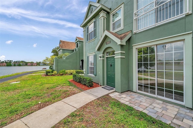 9602 Lake Chase Island Way Unit 9602, Tampa, FL 33626 - doorway to property with stucco siding, a water view, and a lawn