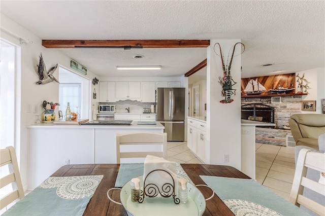 kitchen featuring freestanding refrigerator, healthy amount of natural light, light tile patterned flooring, open floor plan, and a textured ceiling