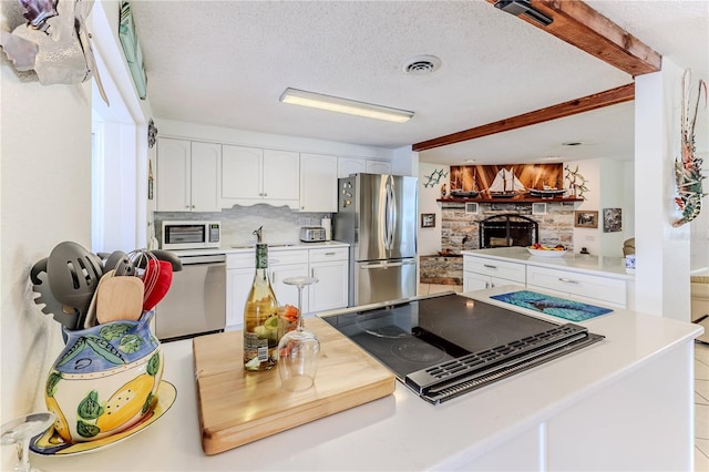 kitchen featuring stainless steel appliances, tasteful backsplash, white cabinetry, a textured ceiling, and light countertops