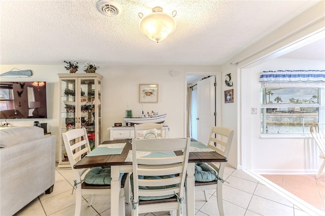 dining room featuring a textured ceiling and light tile patterned floors