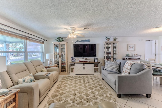 living room featuring light tile patterned flooring, ceiling fan, and a textured ceiling