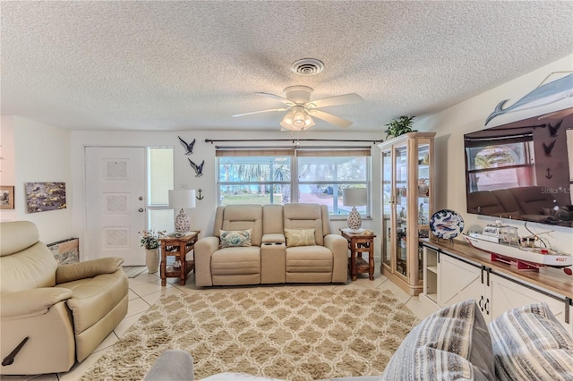 living area with light tile patterned floors, ceiling fan, and a textured ceiling