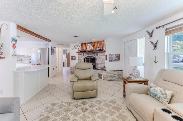 living area featuring light tile patterned floors, a stone fireplace, and a textured ceiling