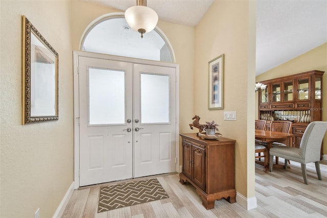 160 Sage Cir, Crystal Beach, FL 34681 - foyer featuring light wood-type flooring, lofted ceiling, baseboards, french doors, and healthy amount of natural light
