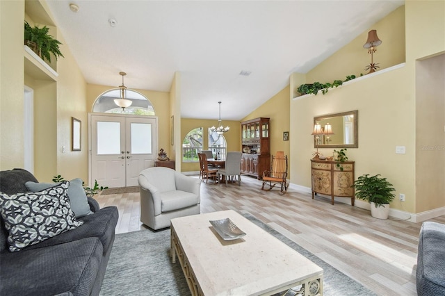 160 Sage Cir, Crystal Beach, FL 34681 - living area with light wood finished floors, a chandelier, baseboards, french doors, and vaulted ceiling