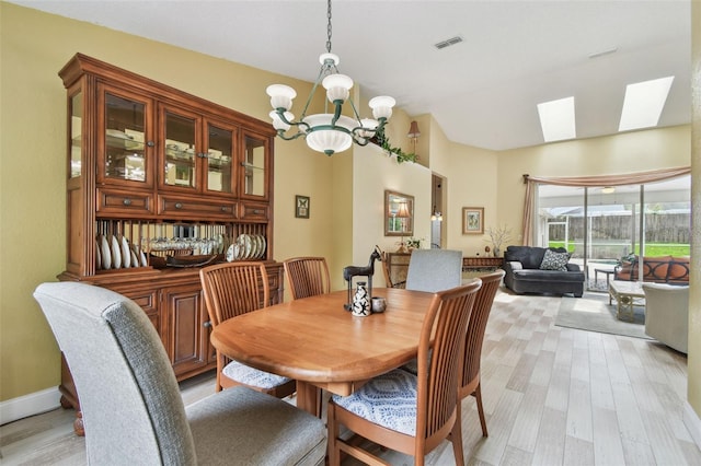 160 Sage Cir, Crystal Beach, FL 34681 - dining space with a chandelier, light wood-type flooring, vaulted ceiling, and a skylight