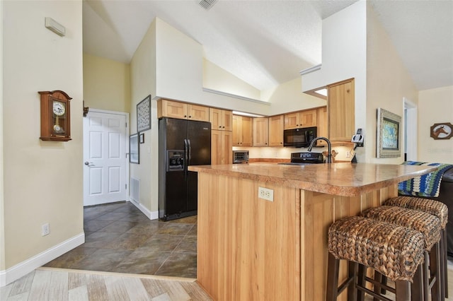 160 Sage Cir, Crystal Beach, FL 34681 - kitchen with black appliances, a peninsula, baseboards, a breakfast bar area, and light countertops