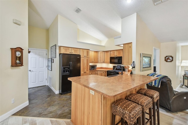 160 Sage Cir, Crystal Beach, FL 34681 - kitchen featuring black appliances, a peninsula, baseboards, a breakfast bar area, and light countertops