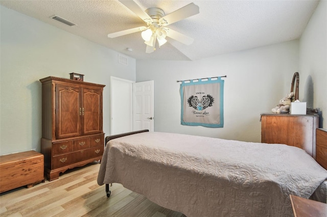 160 Sage Cir, Crystal Beach, FL 34681 - bedroom with light wood finished floors, ceiling fan, and a textured ceiling