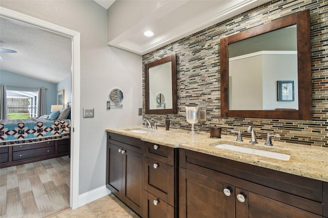 160 Sage Cir, Crystal Beach, FL 34681 - full bathroom featuring connected bathroom, backsplash, double vanity, vaulted ceiling, and baseboards