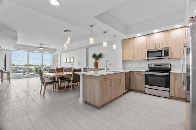 415 Island Way Unit 303, Clearwater Beach, FL 33767 - kitchen featuring stainless steel appliances, a sink, a peninsula, light brown cabinets, and light countertops