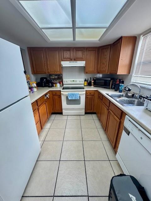 144 Douglas Rd W Unit F, Oldsmar, FL 34677 - kitchen with white appliances, under cabinet range hood, light countertops, and light tile patterned flooring