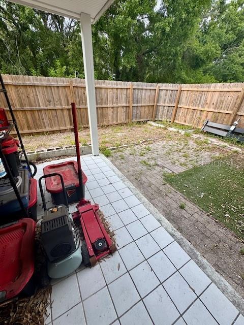 144 Douglas Rd W Unit F, Oldsmar, FL 34677 - view of patio / terrace featuring a fenced backyard and view of scattered trees