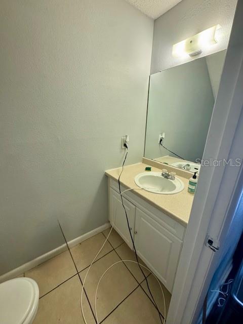 144 Douglas Rd W Unit F, Oldsmar, FL 34677 - bathroom with tile patterned flooring, vanity, a textured ceiling, toilet, and baseboards