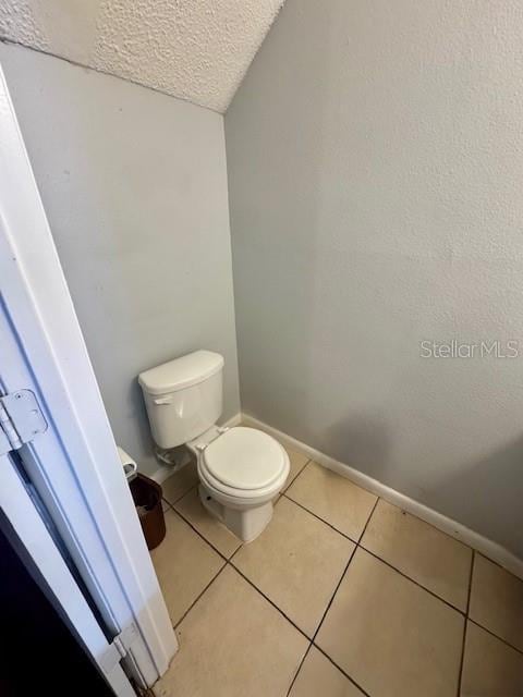 144 Douglas Rd W Unit F, Oldsmar, FL 34677 - bathroom featuring a textured ceiling, toilet, tile patterned floors, and baseboards